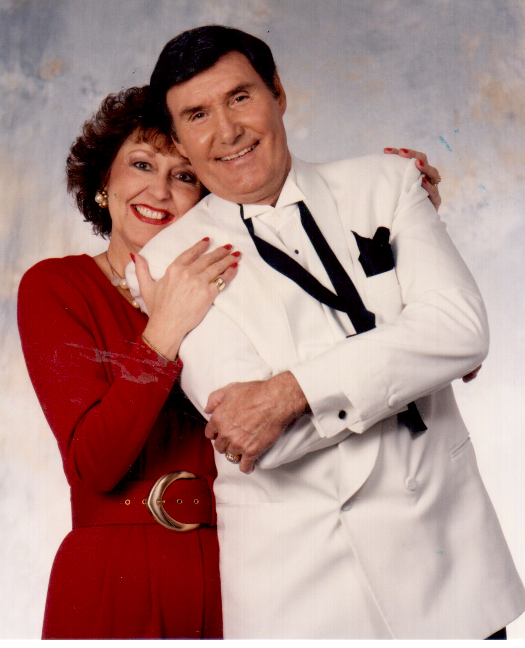 Billy Walker smiling in a white tuxedo with his wife
